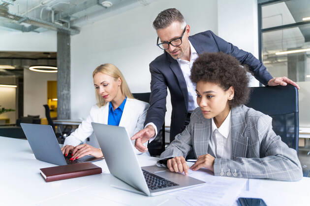 Male business professional explaining female colleague over laptop at desk model released Symbolfoto property released OIPF01191