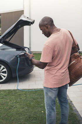 IMAGO Creative: Business, Innovative Technologie-Lösungen Rear view of man using smart phone while standing with backpack at charging station Sweden, Skane, model released, property released Copyright: xMaskotx , MA89569