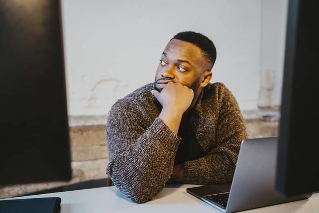 Contemplative male programmer looking away while sitting at desk in creative office Germany, Berlin, model released, property released Copyright: xMaskotx , MA90133