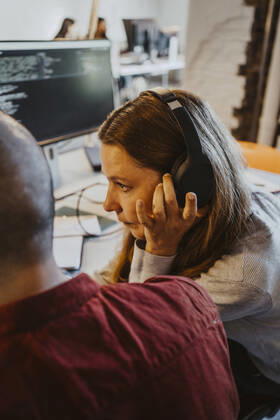 Female programmer listening through headphone while doing coding at startup company Germany, Berlin, model released, property released Copyright: xMaskotx , MA90154