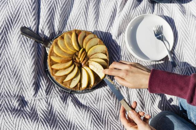 IMAGO Creative, Herbst, Food, Apfelkuchen Hands of woman cutting freshly baked apple pie on picnic blanket model released, EVGF03912