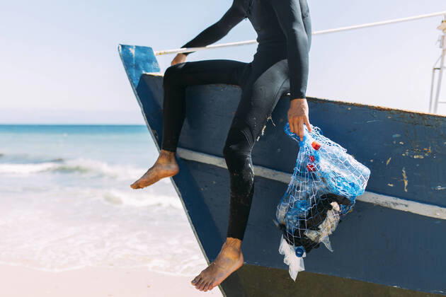 IMAGO Creative: Nächste Generation, Sozial- und klimabewusst Young male volunteer holding mesh bag on boat model released, EGHF00240