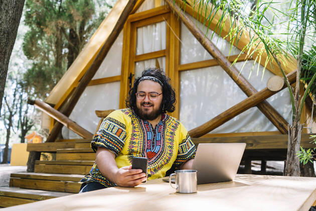 Smiling man with laptop using mobile phone at table model released property released, DAMF00908