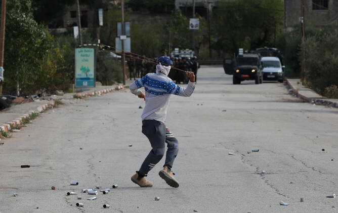 (211125) -- NABLUS, Nov. 25, 2021 -- A protester uses a slingshot to hurl a stone at members of the Israeli border police during clashes in the village of al-Lubban al-Sharqiya near the West Bank city of Nablus, on Nov. 25, 2021. (Photo by Xinhua) MIDEAST-NABLUS-CLASHES NidalxEshtayeh