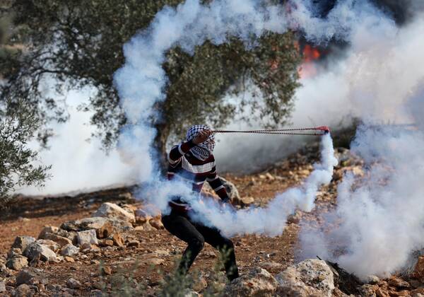 (211126) -- NABLUS, Nov. 26, 2021 -- A protester uses a slingshot to throw back a tear gas canister fired by Israeli soldiers in a protest against the expansion of Jewish settlements in the village of Beita, south of the West Bank city of Nablus, Nov. 26, 2021. (Photo by Ayman Nobani Xinhua) MIDEAST-NABLUS-CLASHES ChenxLin