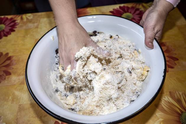 mix and knead the ingredients for stollen dough with your hands in a white bowl 1049002938