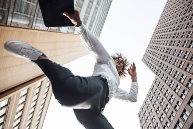 Excited businessman holding digital tablet jumping amidst office buildings model released, GUSF06710