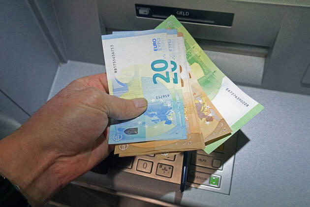Cash supply from a cash dispenser A person withdraws a large amount of cash from a cash dispenser in 100, 50 and 20 euro notes