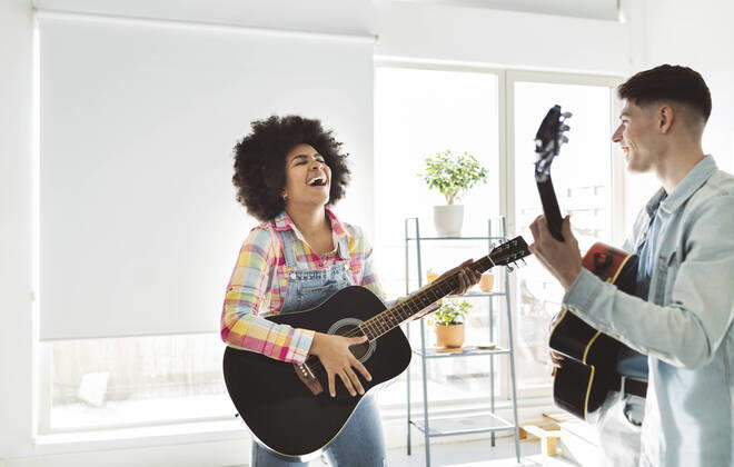 IMAGO Creative: Bildung, Musikerziehung Cheerful young couple playing guitar together at home model released property released, JCCMF05034