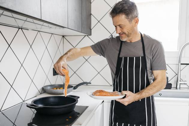 Smiling man cooking fish in kitchen at home model released property released, JRFF05250