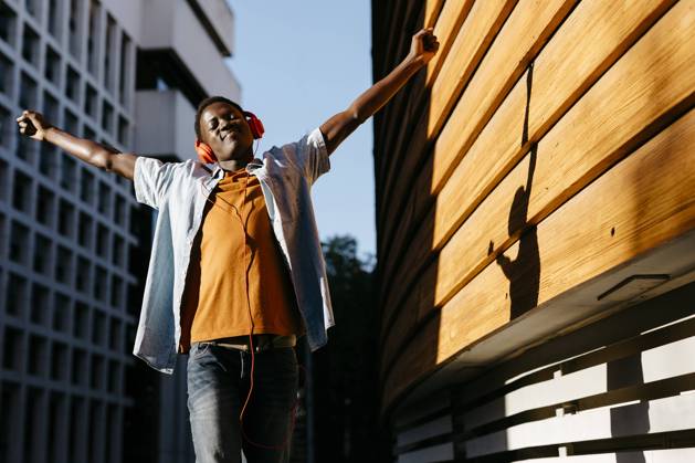 Cheerful man with arms outstretched enjoying music through headphones model released, TCEF02142