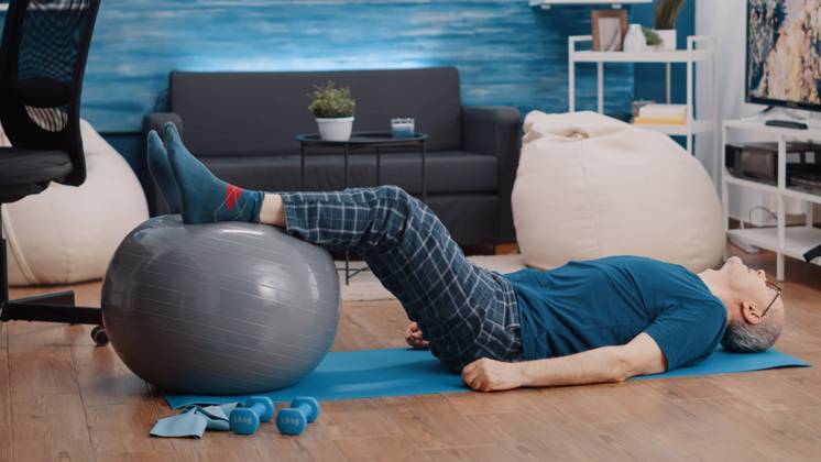 Retired person using fitness toning ball and lifting legs Retired person using fitness toning ball and lifting legs to stretch muscles. Aged man training and doing physical exercise while laying on yoga mat. Pensioner exercising with equipment Copyright: xx 43958050