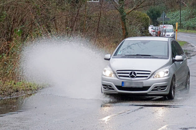 Gefährliche Straßenverhältnisse bei Starkregen Das Wasser von einer nach Starkregen überfluteten Straße wird von den Autos in die Luft gerissen und sorgt bei vielen Fahrern für Schrecksekunden. Essen Nordrhein-Westfalen Deutschland L191