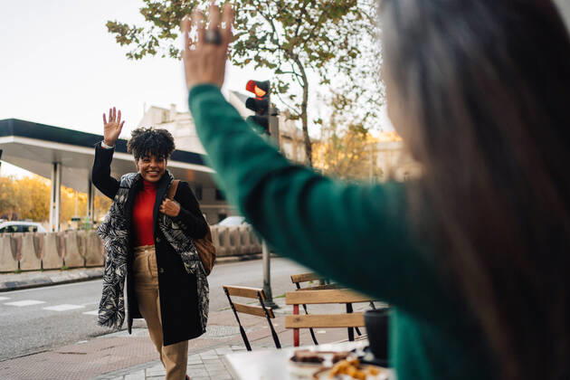 IMAGO Creative, Urban Lifestyle IMAGO Creative: Urban Diversity Hispanic female waving hand to excited African American friend while sitting at table with desserts in street cafe JakeJakab_EliAlicia_25.jpg Copyright: xJakexJakabx Model Released