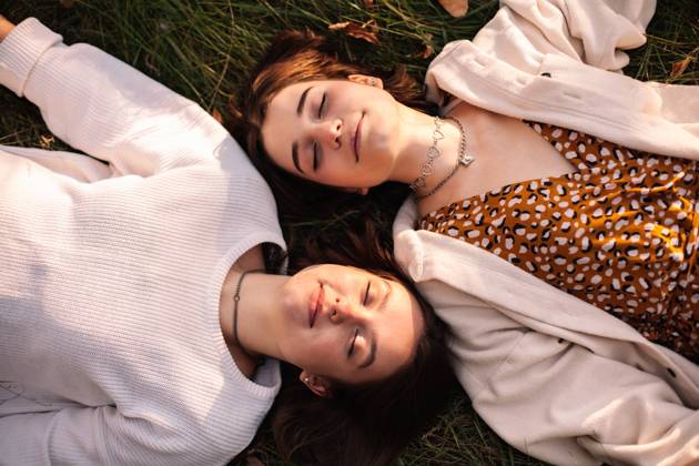 Overhead view of two happy young women lying on grass with eyes closed CR_DMBE220219-918561-01 ,model released, Symbolfoto