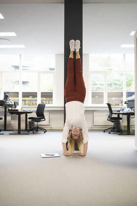 Businesswoman doing handstand in front of a column at office model released property released, JAHF00175