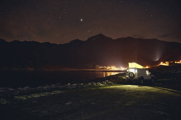 Illuminated off-road vehicle by reservoir at night, Splugen Pass, Sondrio, Switzerland property released, SSCF00853