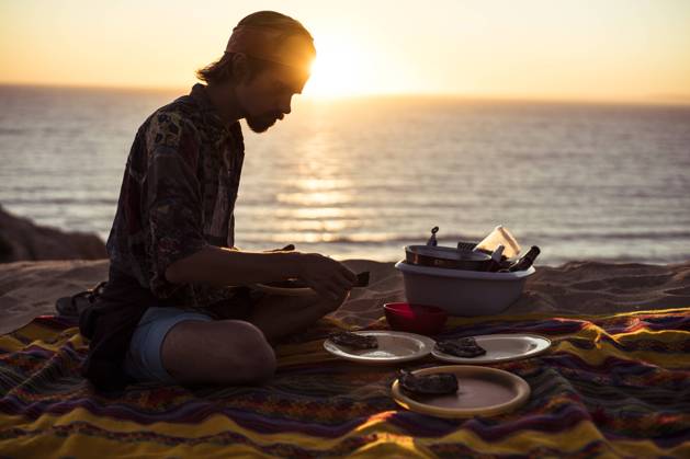 IMAGO Creative: Ende des Sommers Sunset glow over ocean as man makes picnic dinner in sand Portugal Melides, Setubal, Portugal CR_PIDODS220414-672631-01 ,model released, Symbolfoto
