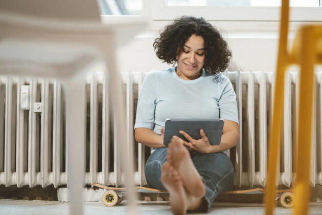 Smiling woman sitting on skateboard with tablet PC at home model released, Symbolfoto property released, JOSEF07855