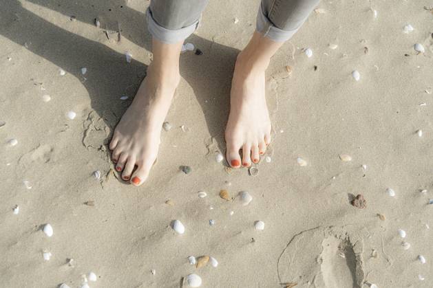 Woman standing barefeet on sand with seashells at beach model released, Symbolfoto, CHPF00845