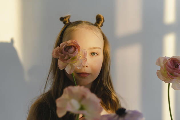 Cute girl holding flower on face standing by white wall model released, Symbolfoto property released, SEAF00740