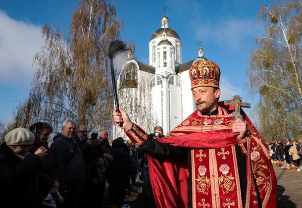 BUCHA, UKRAINE - APRIL 24, 2022 - A priest blesses people and their baskets with holy water outside the Church of Saint Andrew the First-Called Apostle during the Orthodox Easter celebration in Bucha that is recovering from the war crimes committed by Russian troops after its liberation from Russian invaders, Kyiv Region, northern Ukraine. Easter service in Bucha  Copyright: xHennadiixMinchenkox