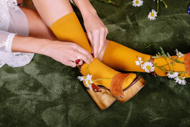 Crop anonymous bride in white elegant dress and colorful socks putting small flowers into shoes while sitting in light studio HodeiUnzueta_BrideWithFlowersAtStudio_00022.jpg Copyright: xHodeixUnzuetax Model Released