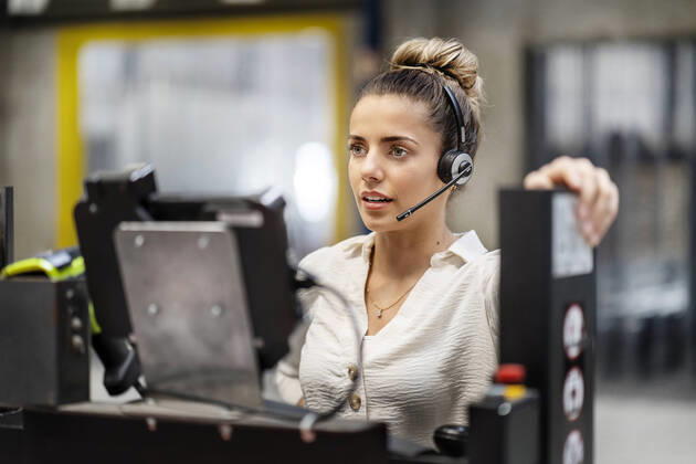 IMAGO Creative: Business, Inflation und Lieferketten Young businesswoman wearing headset operating machine in factory model released, Symbolfoto property released, PESF03754