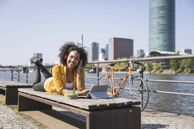 IMAGO Creative: Business - Work-Life Balance Smiling businesswoman listening music and using laptop on sunny day model released, Symbolfoto, UUF25929
