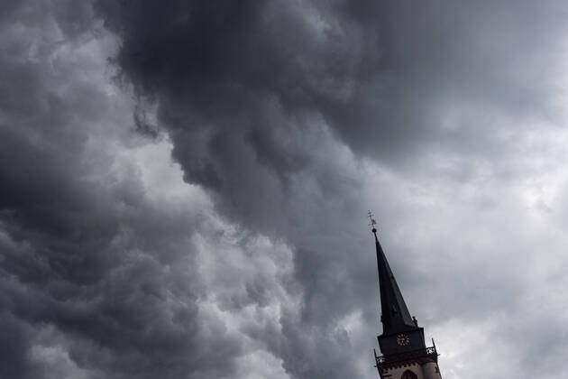 Dark clouds over the church tower Dark clouds of a shower are seen in the evening in the sky above the steeple of the Catholic Church St Ursula in Oberursel , Oberursel Hesse Germany