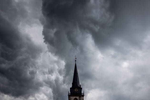 Dark clouds over the church tower Dark clouds of a shower are seen in the evening in the sky above the steeple of the Catholic Church St Ursula in Oberursel , Oberursel Hesse Germany