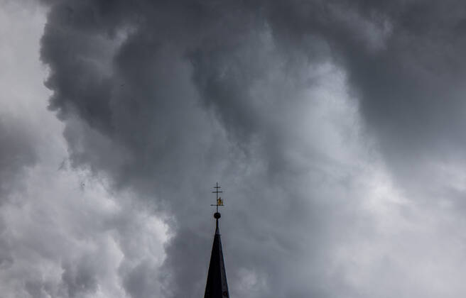 Dark clouds over the church tower Dark clouds of a shower are seen in the evening in the sky above the steeple of the Catholic Church St Ursula in Oberursel , Oberursel Hesse Germany