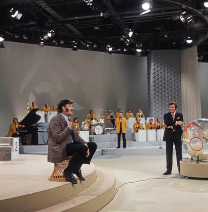 DREI MAL NEUN Drei mal Neun, ZDF Quizshow, Deutschland, 1971, im Bild: Showgast Jürgen von Manger, im Hintergrund Max Greger mit Bigband und Showmaster Wim Thoelke. Drei mal Neun, TV quiz show, Germany, 1971, on the photo: show guest, German comedian and cabaret artist Juergen von Manger, background: Max Greger with Big band and presenter Wim Thoelke., Deutschland Copyright: ArthurxGrimm UnitedArchives82007889 EDITORIAL USE ONLY