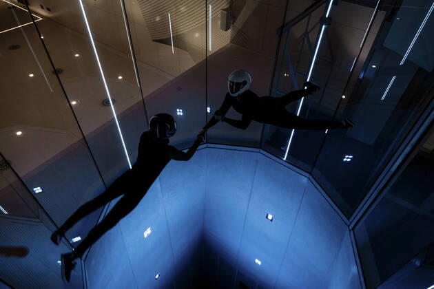 IMAGO Creative: Business, Innovative Technologie-Lösungen Athletes holding each others hands flying in illuminated wind tunnel model released, Symbolfoto property released, MRRF02117
