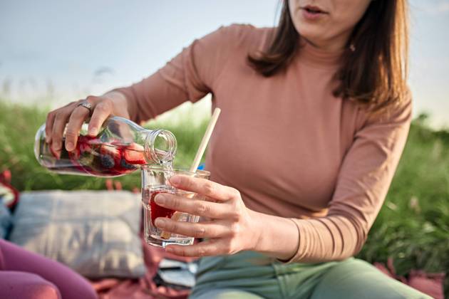 Young woman pouring infused water in glass at field on weekend model released, Symbolfoto, ZEDF04562