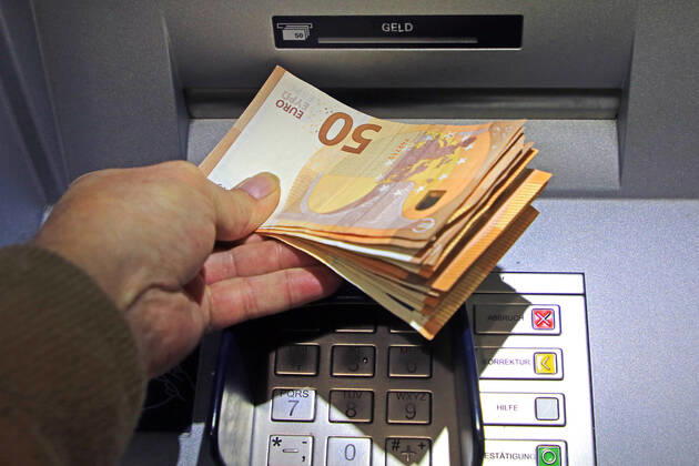 Cash supply from a cash dispenser A person withdraws a large amount of cash from a cash dispenser in 50 euro bills