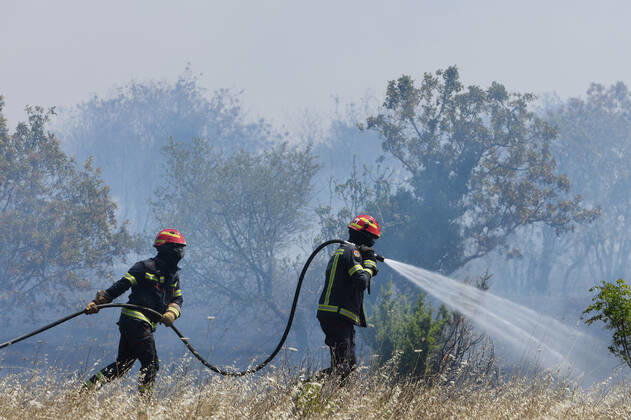 PXL_A fire near Vodice, Croatia Fire in an open area near the Velika Mrdakovica archaeological site in the Vodice hinterland, Croatia on July 13, 2022. About 30 firefighters with a dozen vehicles are on the ground, and two Canadairs joined the ground forces in extinguishing the fire. There are pine forests above, low vegetation, and endangered buildings. HrvojexJelavic PIXSELL