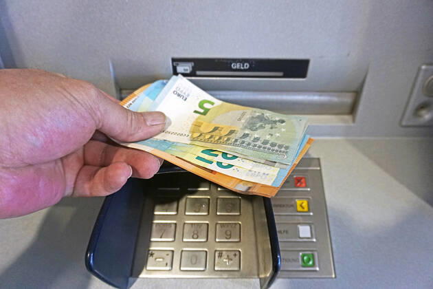 Cash supply from an ATM A person withdraws cash from an ATM in 50, 20 and 5 euro bills