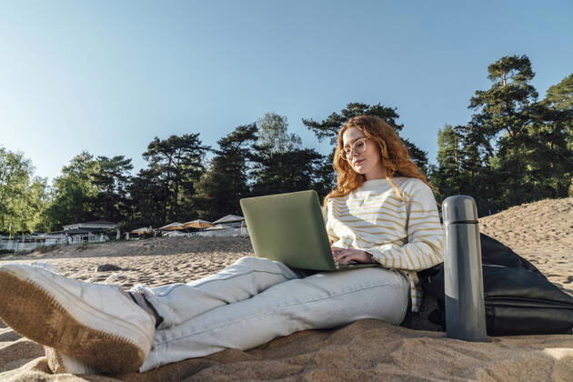 Woman e-learning over laptop at beach model released, Symbolfoto, VPIF06573