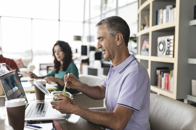 Happy businessman eating salad at desk in office model released, Symbolfoto property released, JCICF00188