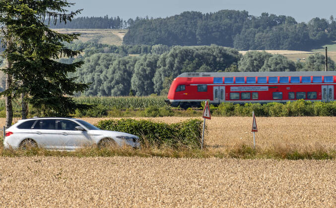 Car and regional train in the countryside, on the road in the district of Landshut,