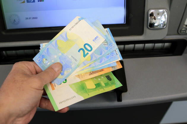 Cash supply from an ATM A person withdraws a large amount of cash from an ATM in 50 and 20 euro bills
