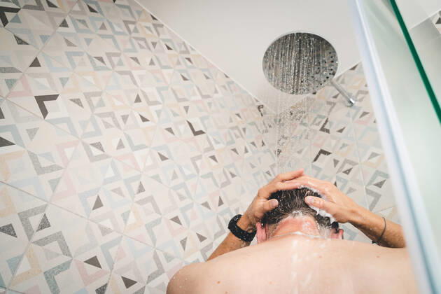 29 July 2022: attractive young man takes a shower under running water in the shower in the bathroom, body care with shampoo