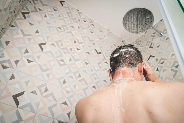 29 July 2022: attractive young man takes a shower under running water in the shower in the bathroom, body care with shampoo