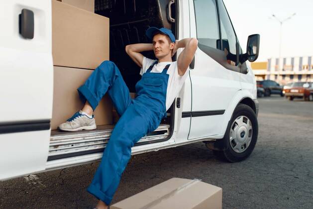 IMAGO Creative: Business, Inflation und Lieferketten Deliveryman relaxing in the car during a break, Deliveryman in uniform relaxing in the car during a break, auto with parcels and carton boxes, delivery service. Man poses at cardboard packages in vehicle, male deliver, courier or shipping job model released, Symbolfoto , 05.02.2020 10:34:29, Copyright: xNomadSoulx Panthermedia28066076.jpg