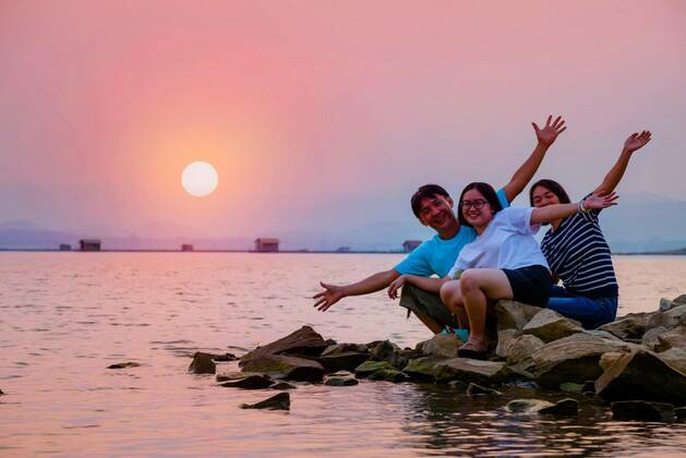  Asian family happy sitting on the waterfront, Asian family father mother and teenage daughter happy sitting on the waterfront at lake water sun in the orange sky beautiful nature landscape at sunset background, Krasiao Dam, Suphan Buri, Thailand model released, Symbolfoto , 31.12.2020, Copyright: xYongkietx Panthermedia29216806.jpg