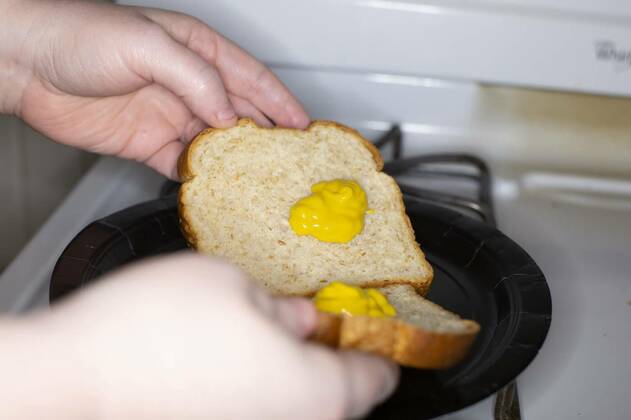 Putting Mustard on a Sandwich, Preparing sandwich bread covered with clumps of mustard model released, Symbolfoto , 14.01.2021, Copyright: xtornado98x Panthermedia29253004.jpg