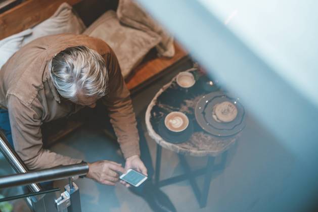 IMAGO Creative: Business, Innovative Technologie-Lösungen Senior man text messaging on smart phone at cafe model released, Symbolfoto property released, JOSEF11561