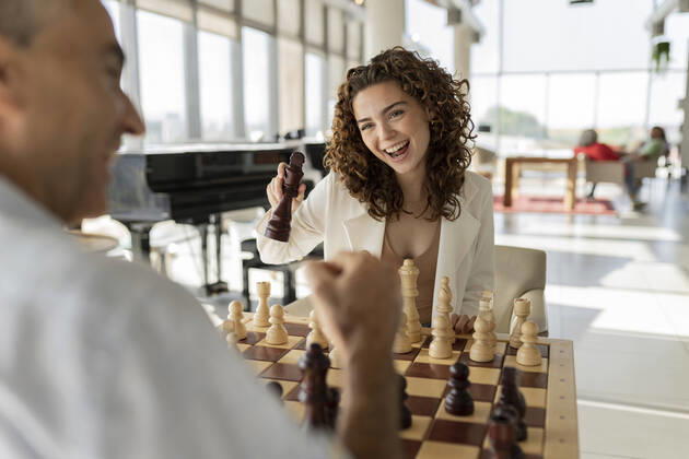 Happy young businesswoman playing chess with mature colleague in office model released, Symbolfoto property released, JCICF00379