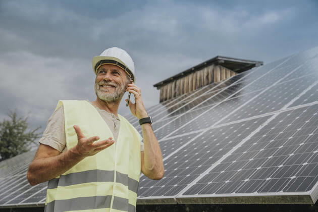 IMAGO Creative: Business, Innovative Technologie-Lösungen Engineer wearing hardhat talking on phone by solar panels model released, Symbolfoto, MFF09274